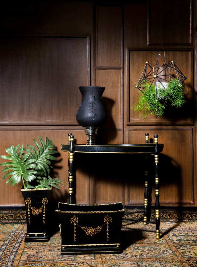 Sophisticated black and gold furniture and decor set against wood paneling in New Delhi